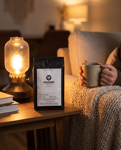 Monark Off Duty Decaf on a side table by lamplight, with a mug of coffee