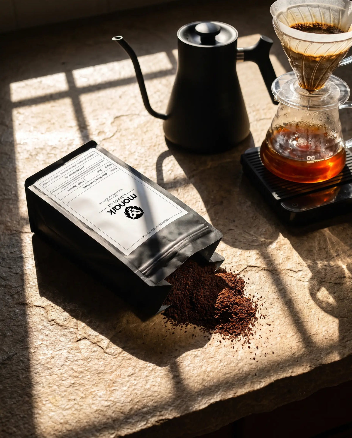 Monark ground coffee spilling from the bag next to a pour-over